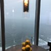 a glass bowl of apples on a table with a light from a window