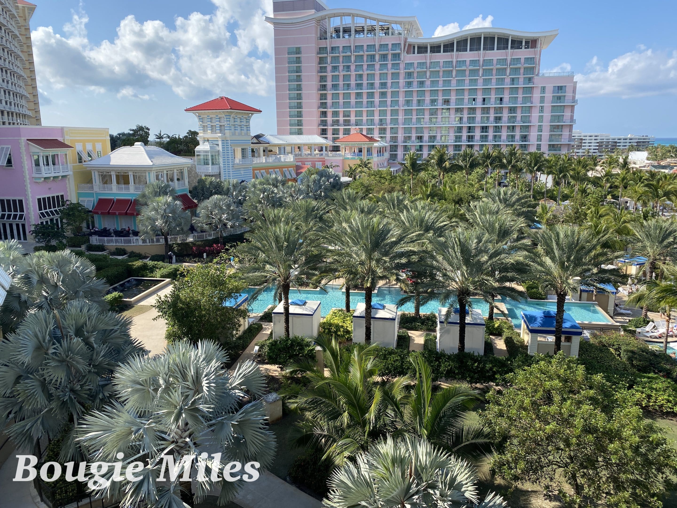 a pool and palm trees in front of a hotel