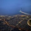 an airplane wing and wing of an airplane flying over a city