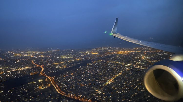 an airplane wing and wing of an airplane flying over a city