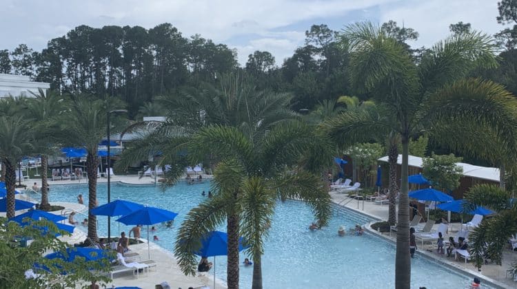 a pool with blue umbrellas and palm trees