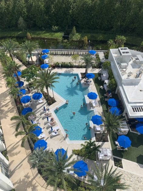 a pool with blue umbrellas and palm trees