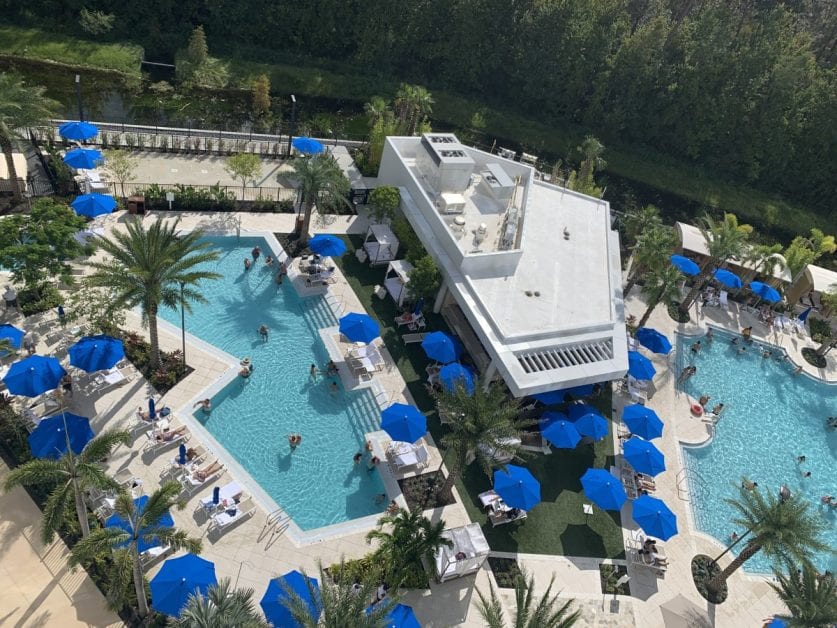 a pool with blue umbrellas and palm trees