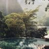 a pool with trees and mountains in the background