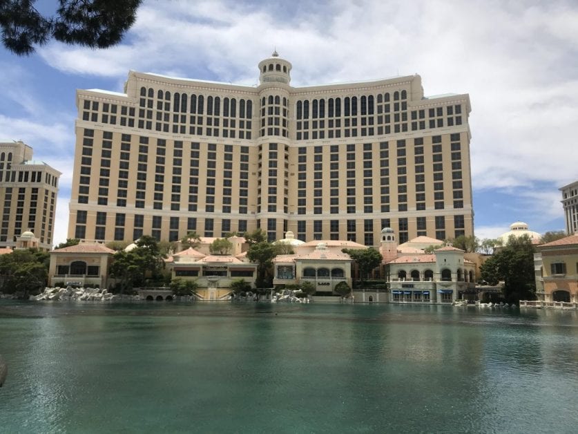 a large building with many windows and a body of water with Bellagio in the background