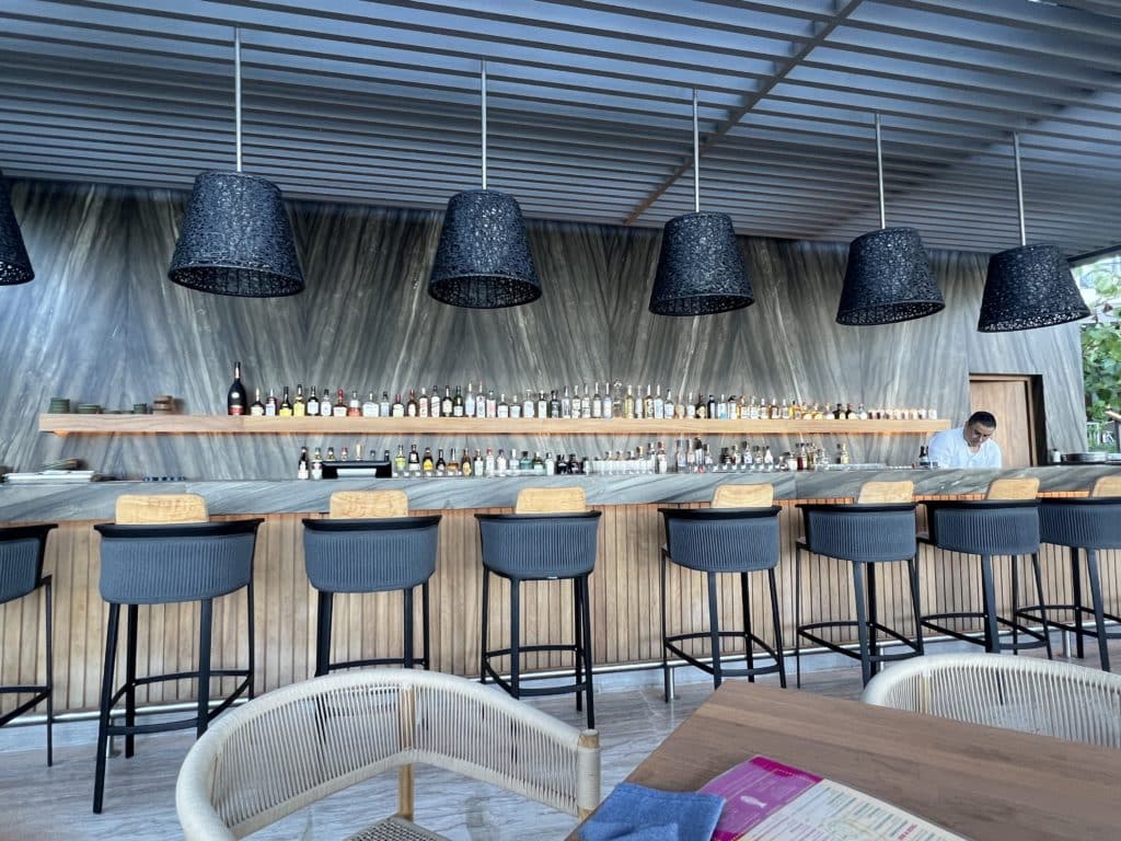 a bar with chairs and a counter with bottles on the wall