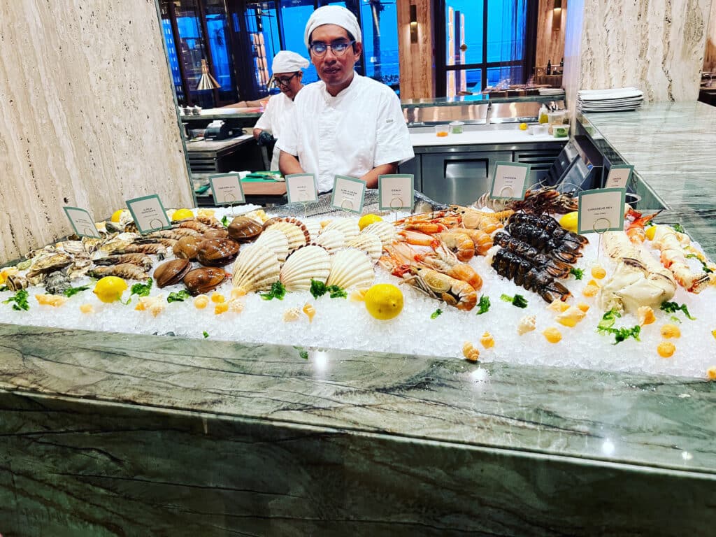 a man standing behind a counter with seafood on ice