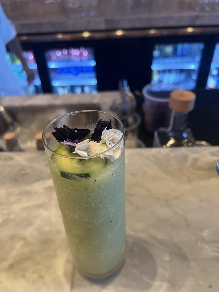 a glass of drink with cucumber and cheese