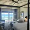 a room with a bed and a couch and a table with a door to the ocean