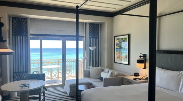 a room with a bed and a couch and a table with a door to the ocean