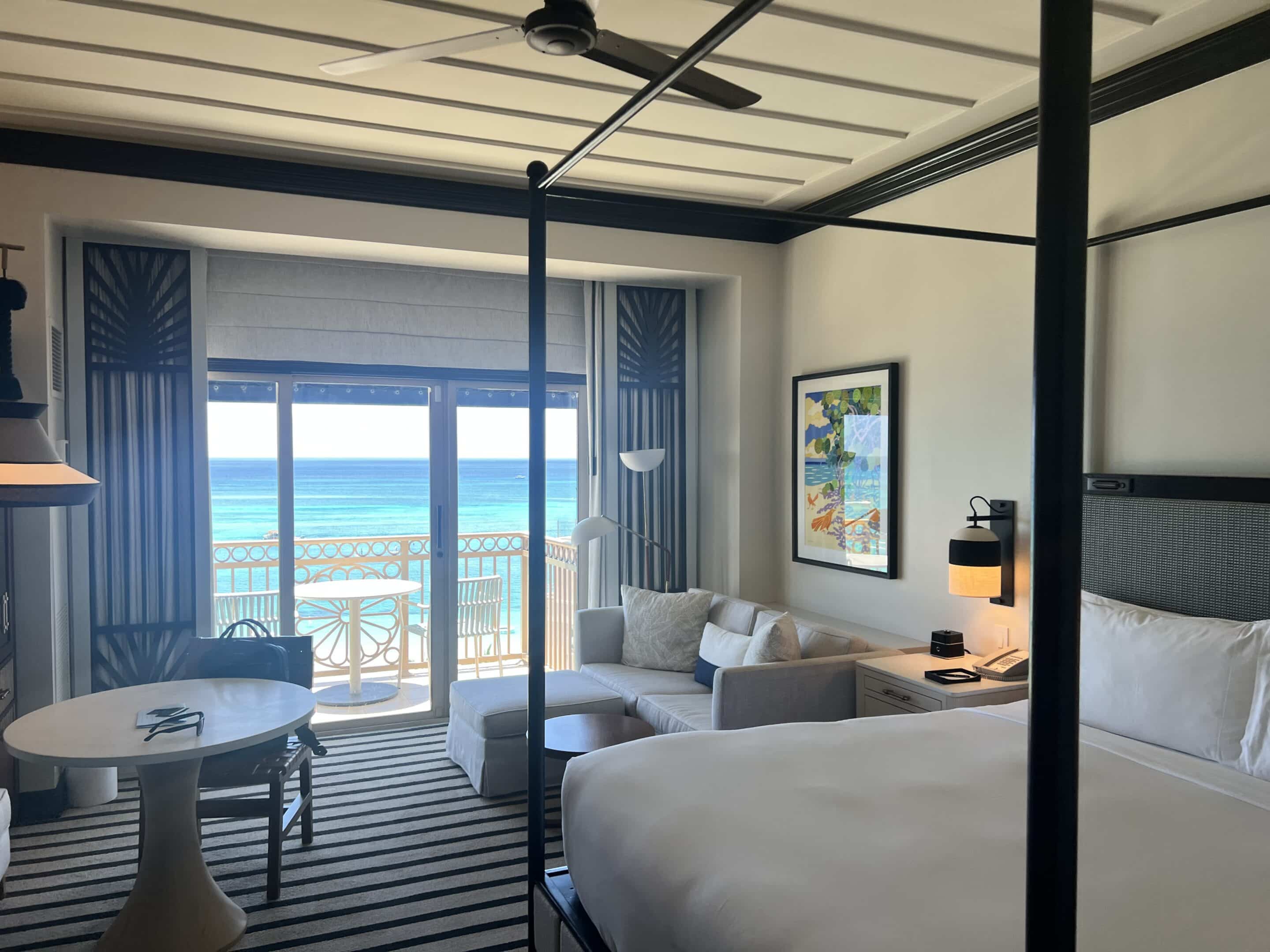 a room with a bed and a couch and a table with a door to the ocean