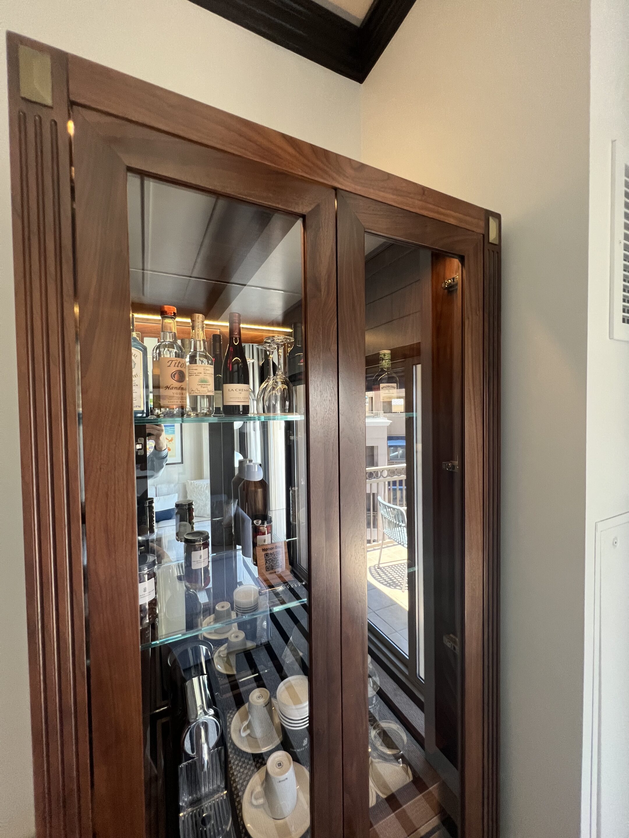 a glass cabinet with bottles and plates