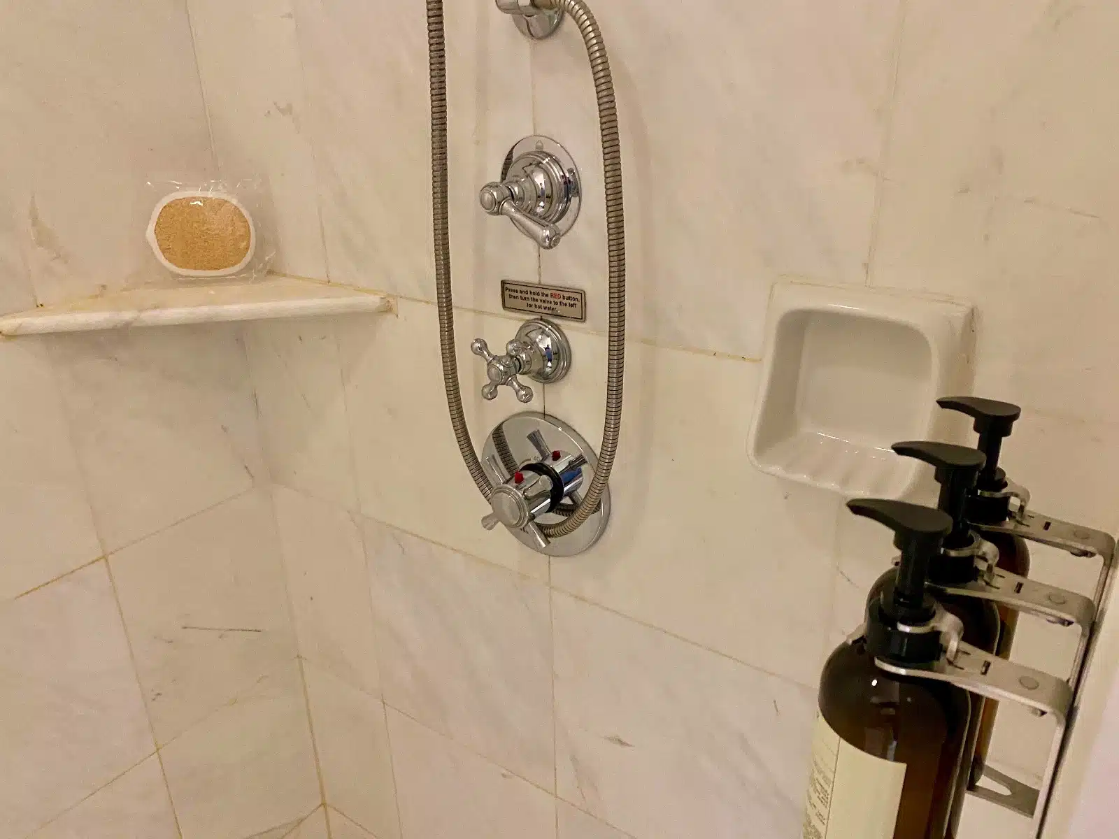 a shower head with a hose and a soap dispenser