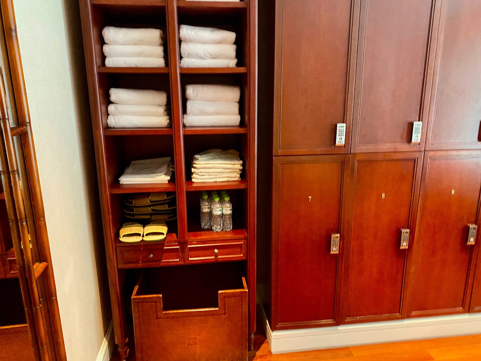 a wooden shelving unit with towels and a pair of cabinets