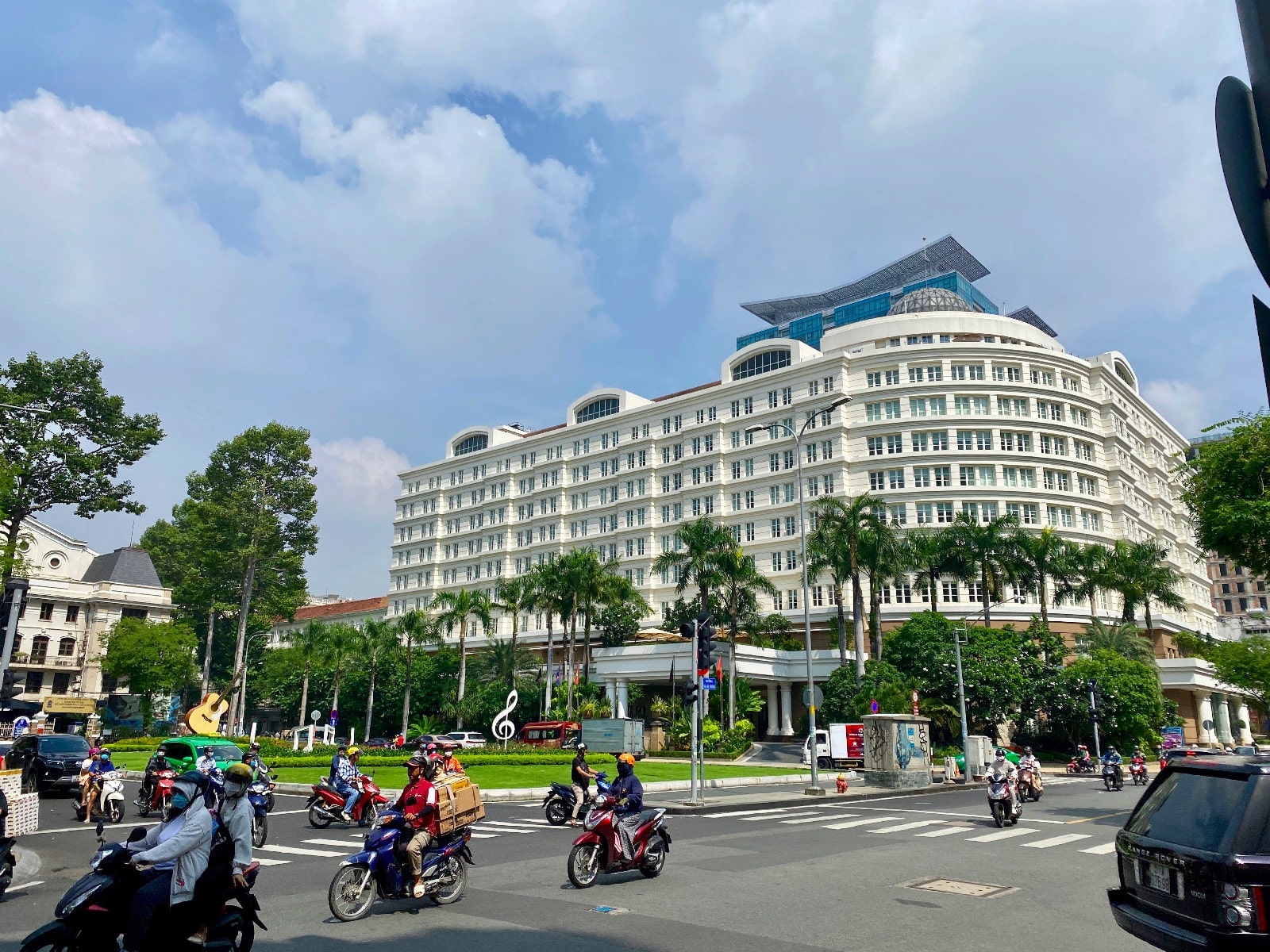 a group of people on motorcycles in a street with trees and buildings