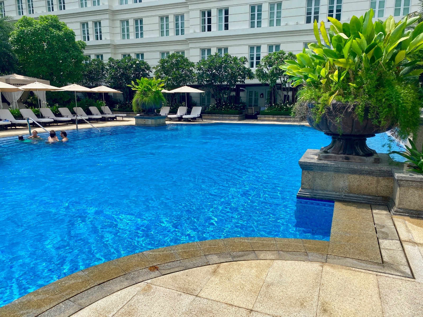 a pool with a large planter and umbrellas