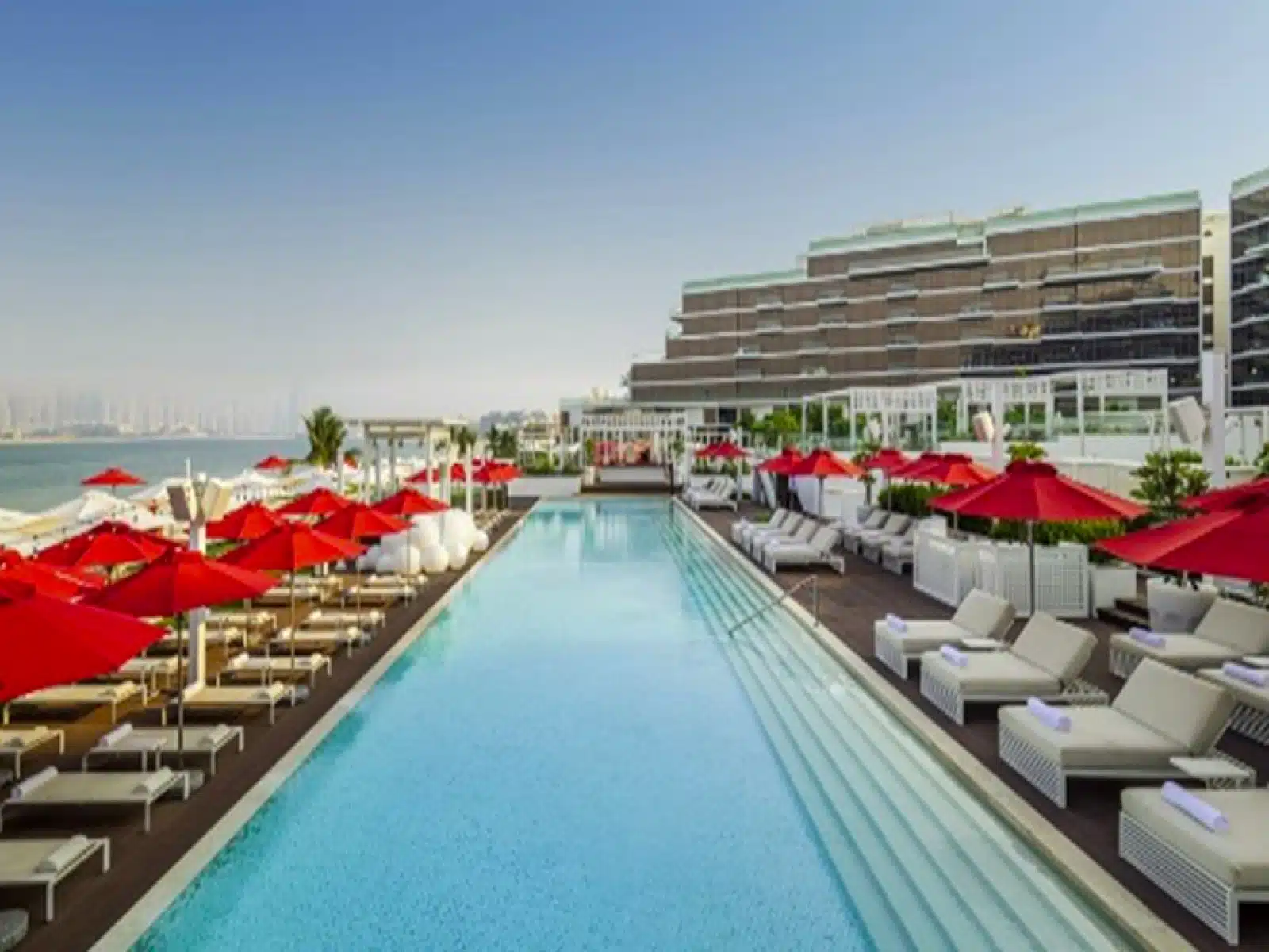 a swimming pool with red umbrellas and chairs