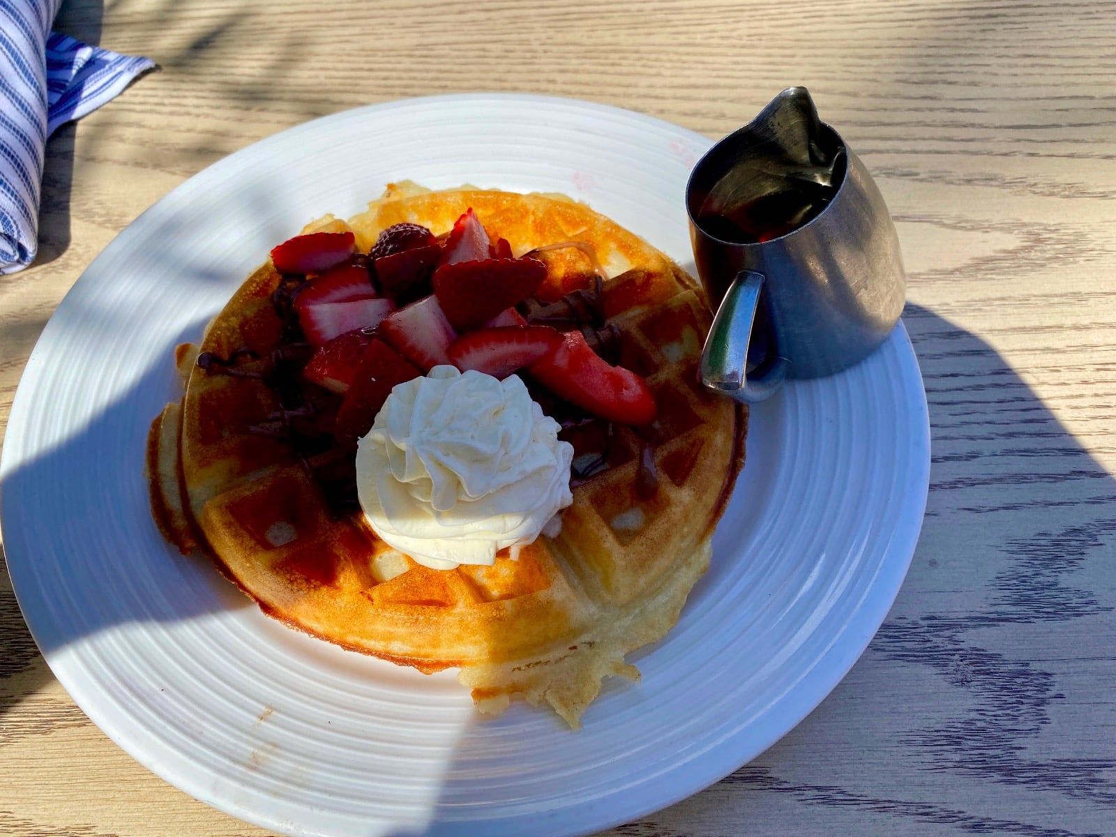 a plate of waffles with strawberries and whipped cream