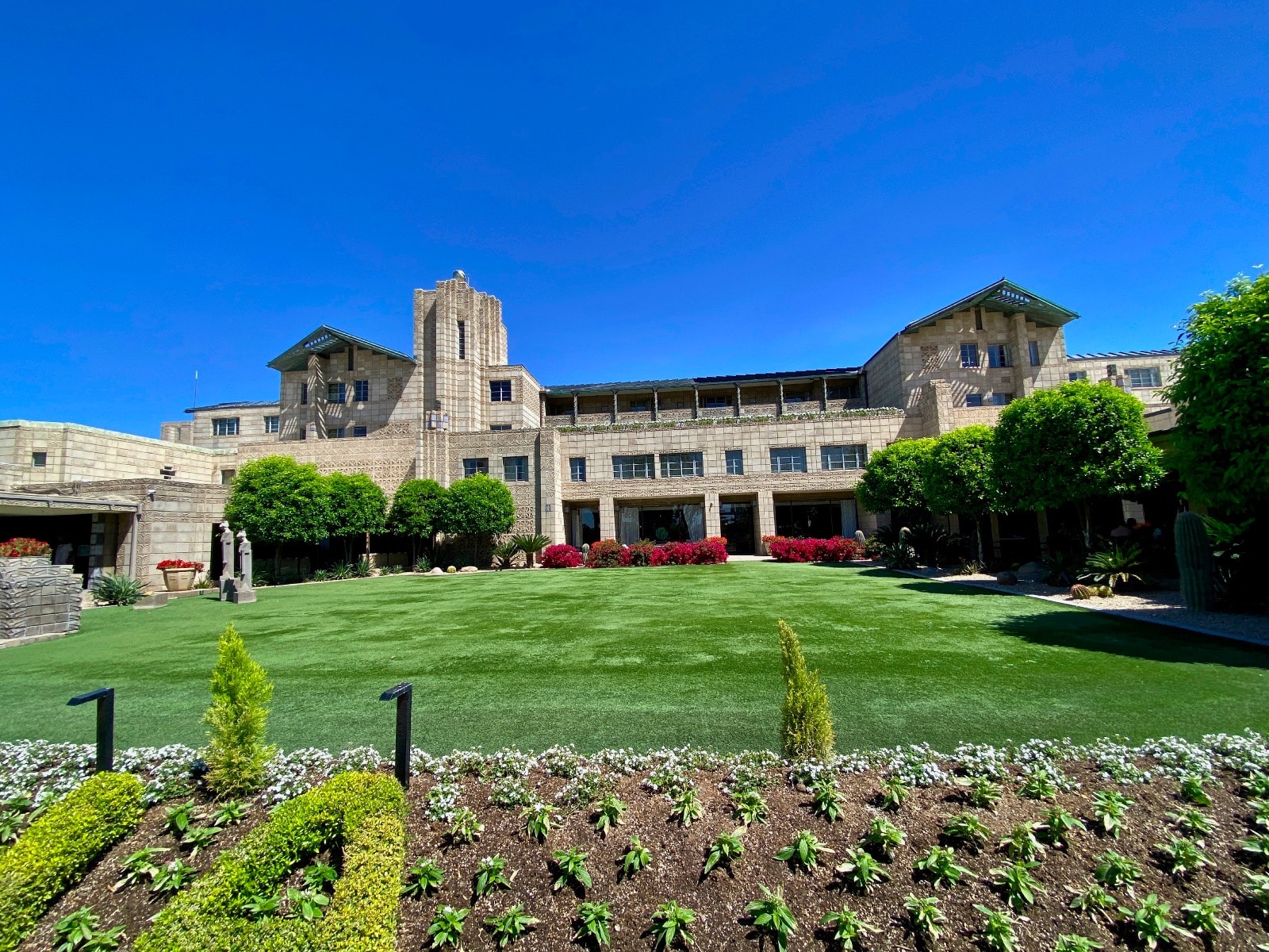 a large building with a lawn and bushes