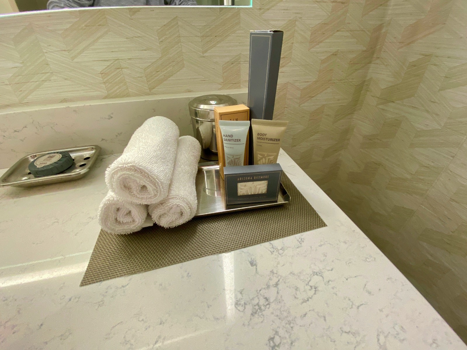 a bathroom counter with a tray of towels and toiletries