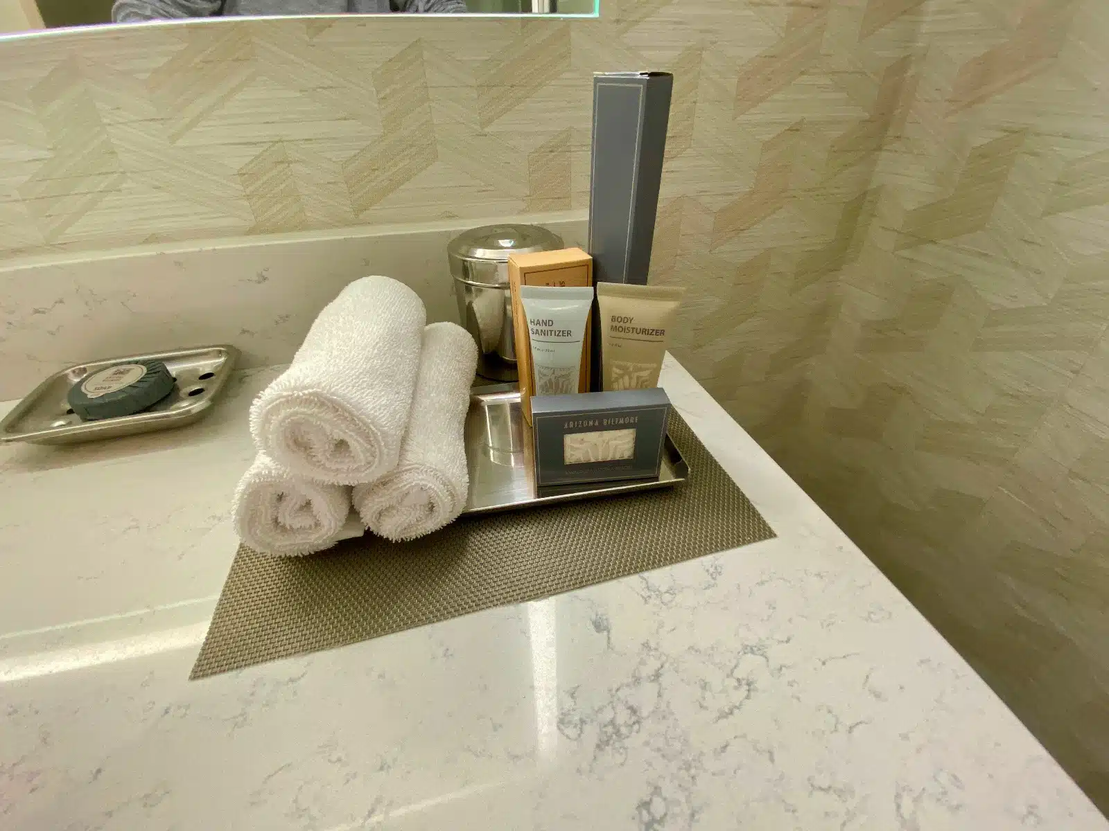 a bathroom counter with a tray of towels and toiletries