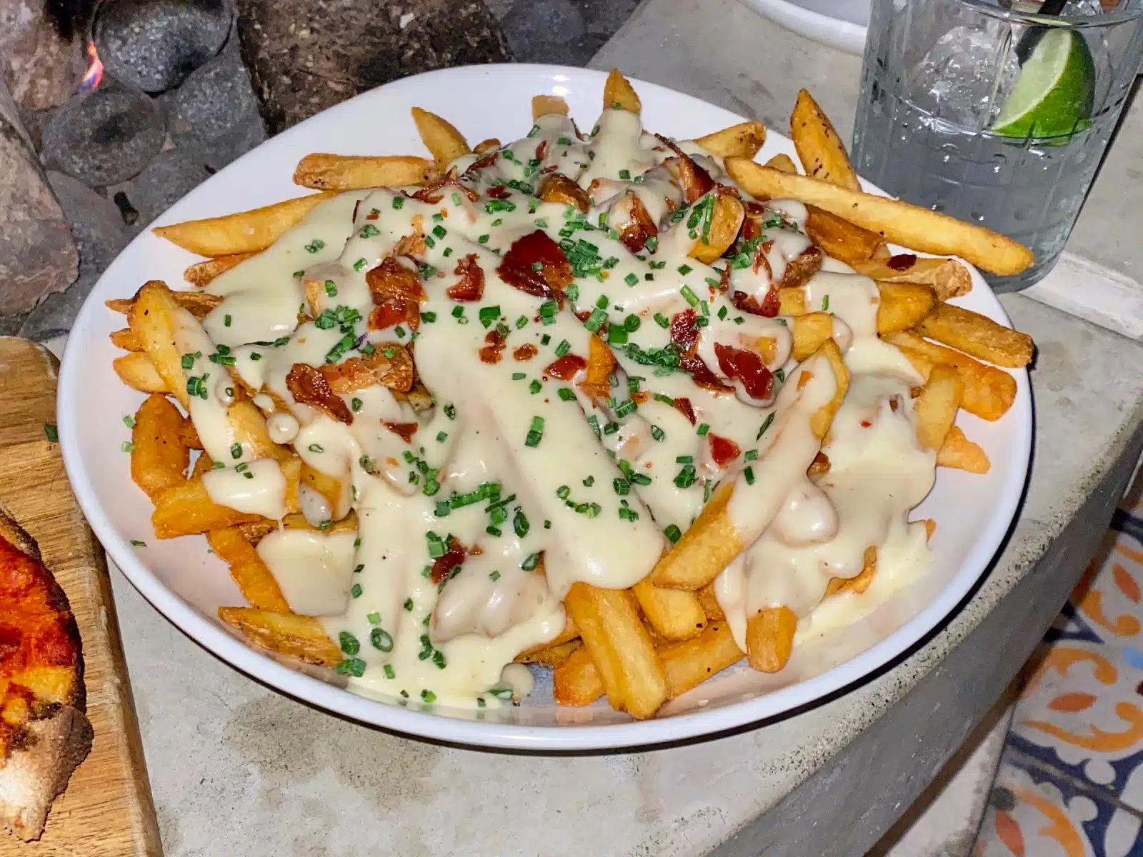 a plate of french fries with white sauce and green onions