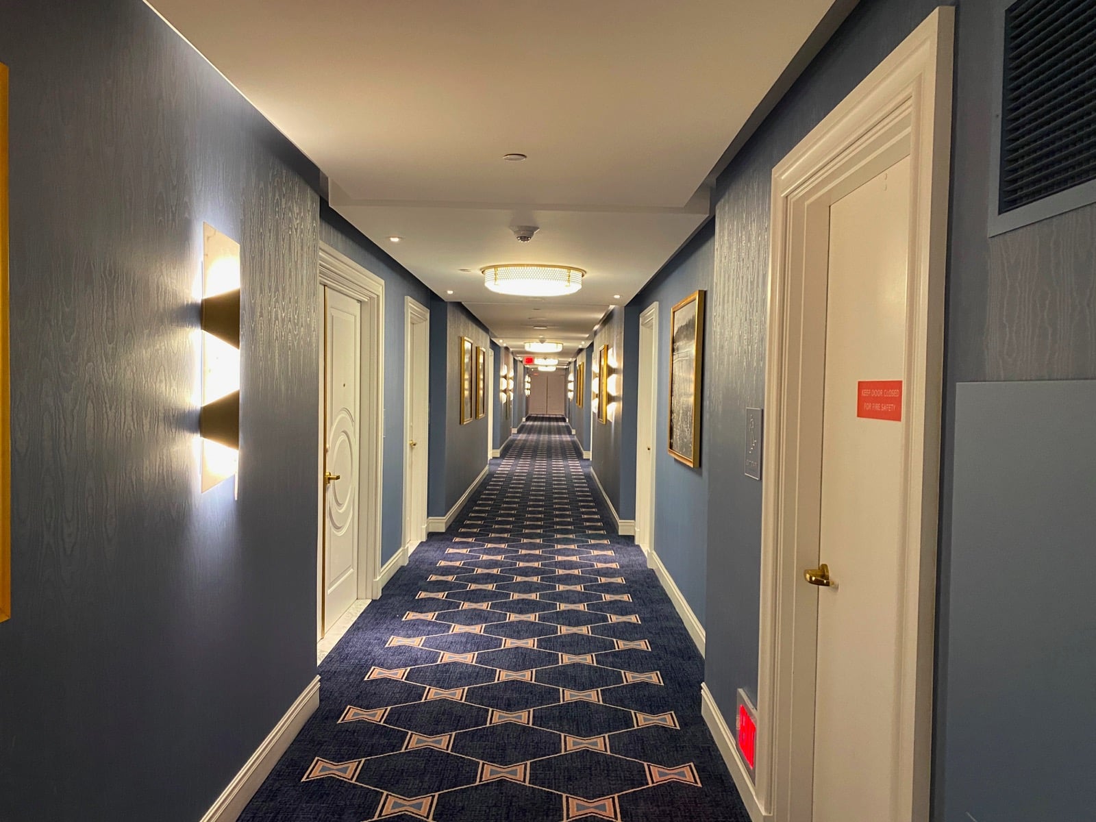 a long hallway with doors and a blue carpet
