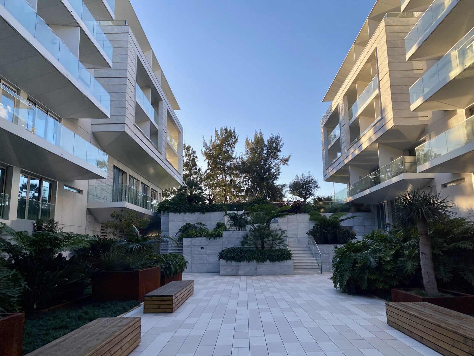 a courtyard with trees and plants in front of buildings
