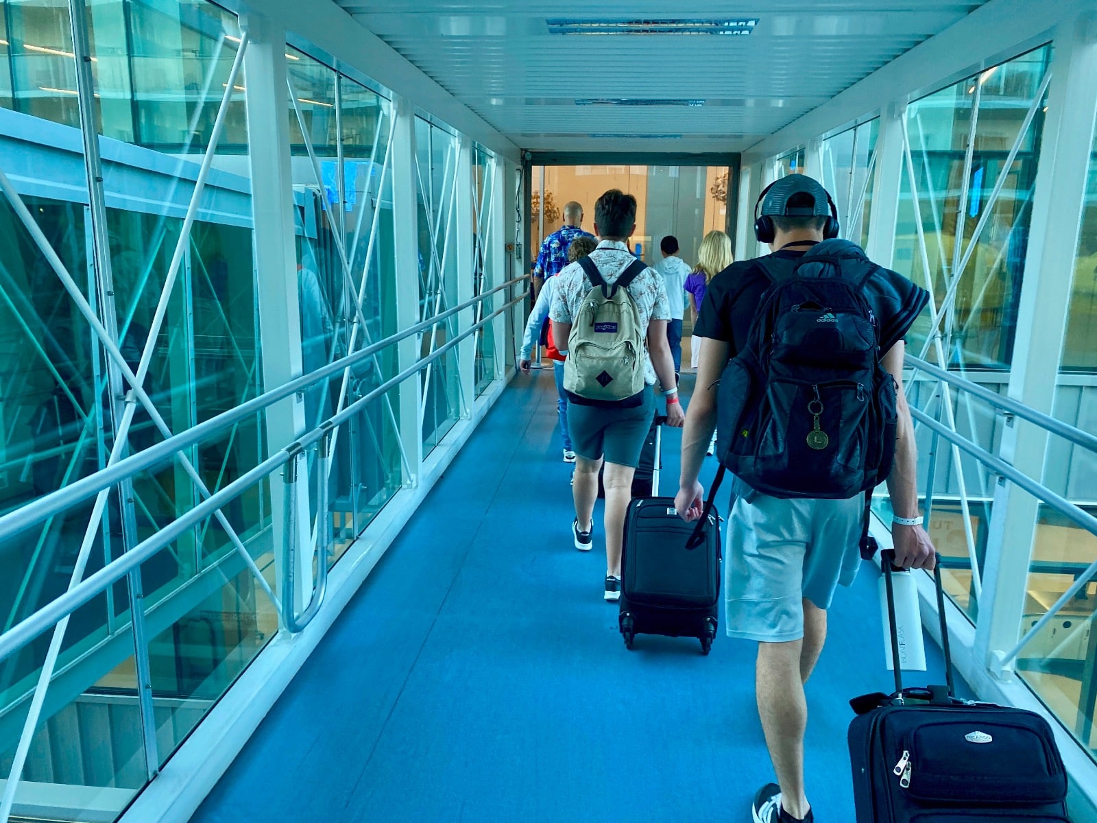 a group of people walking down a walkway with luggage