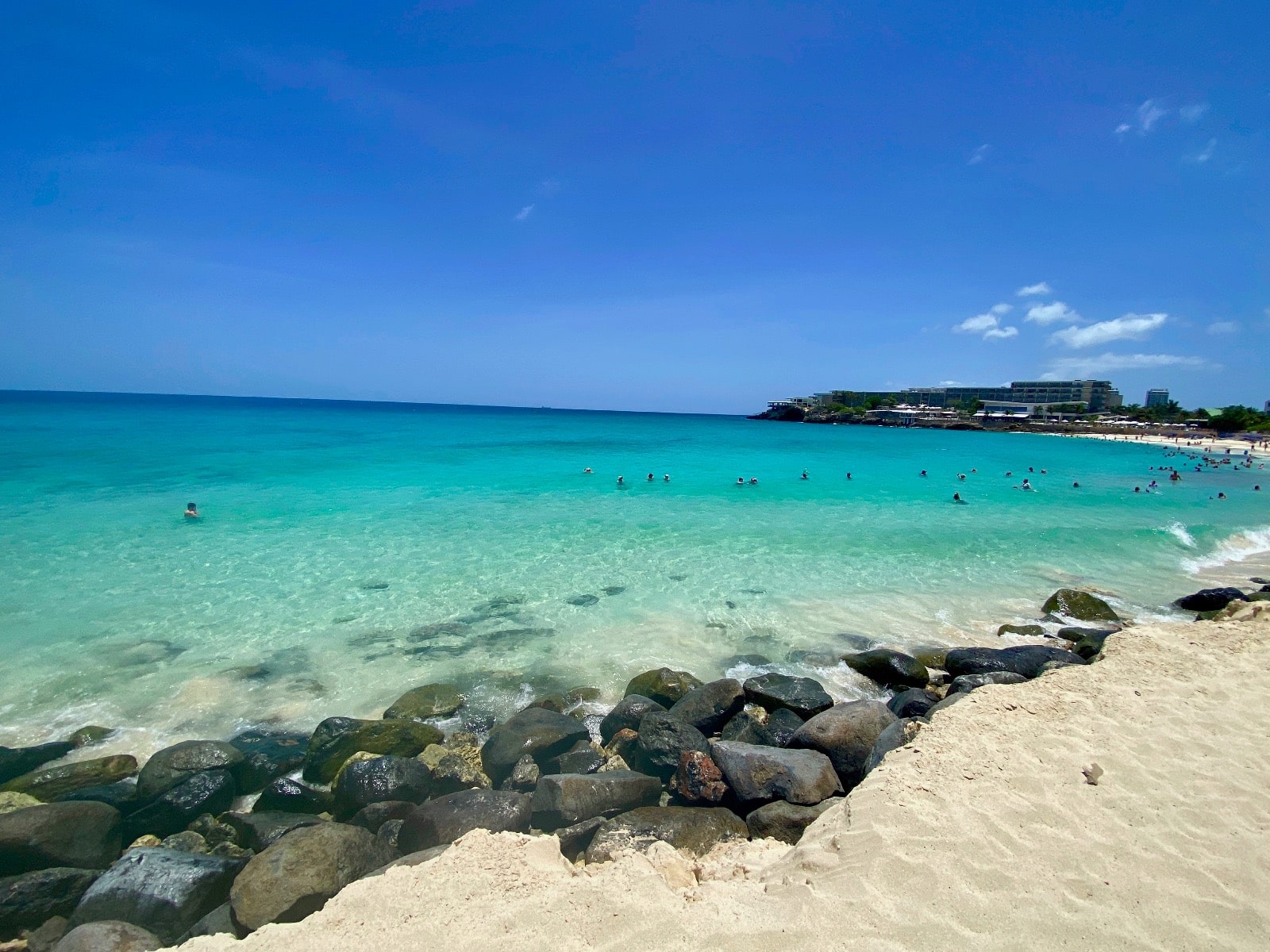 a beach with rocks and people swimming in the water