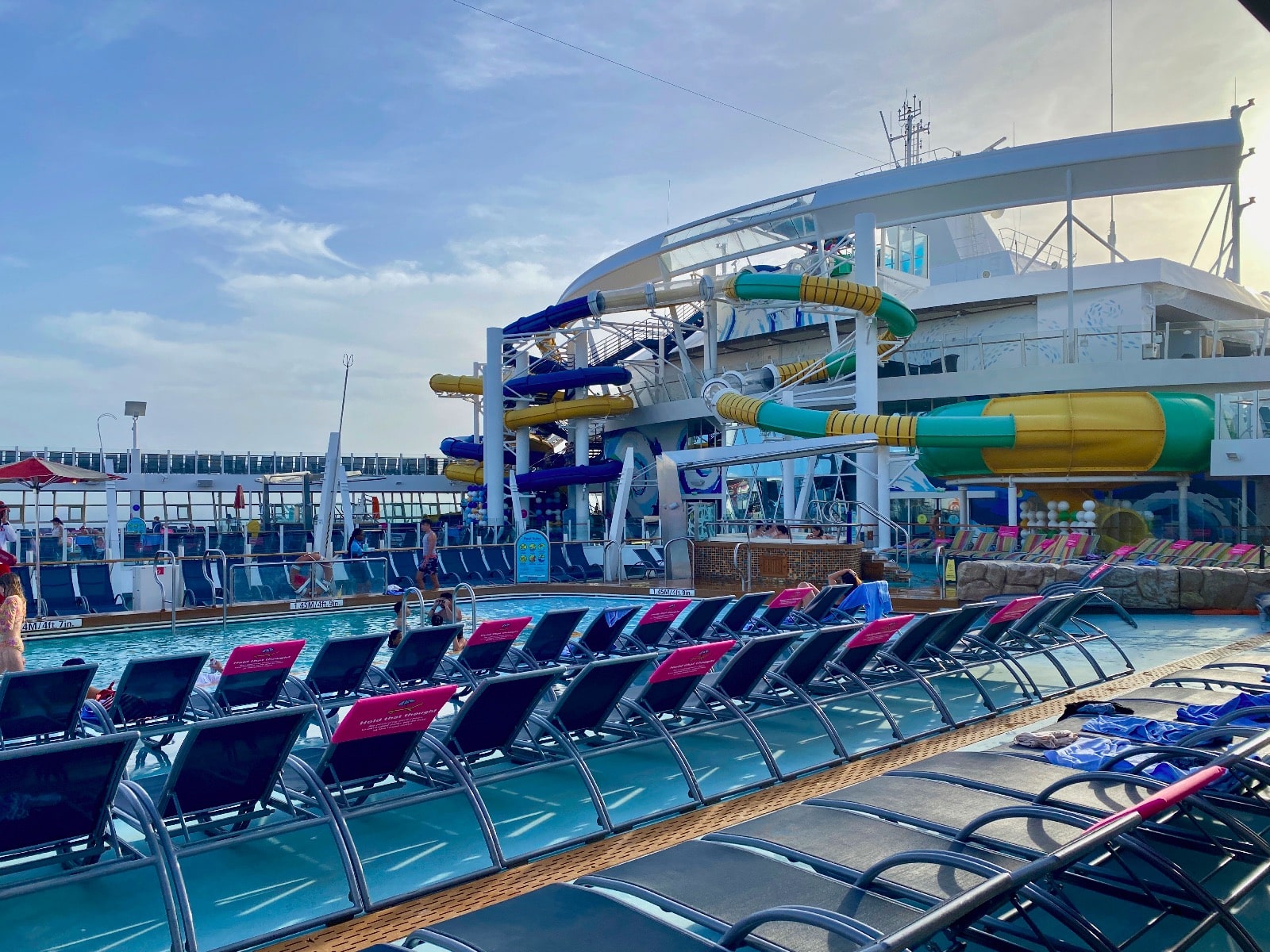 a pool with chairs and water slide on the deck