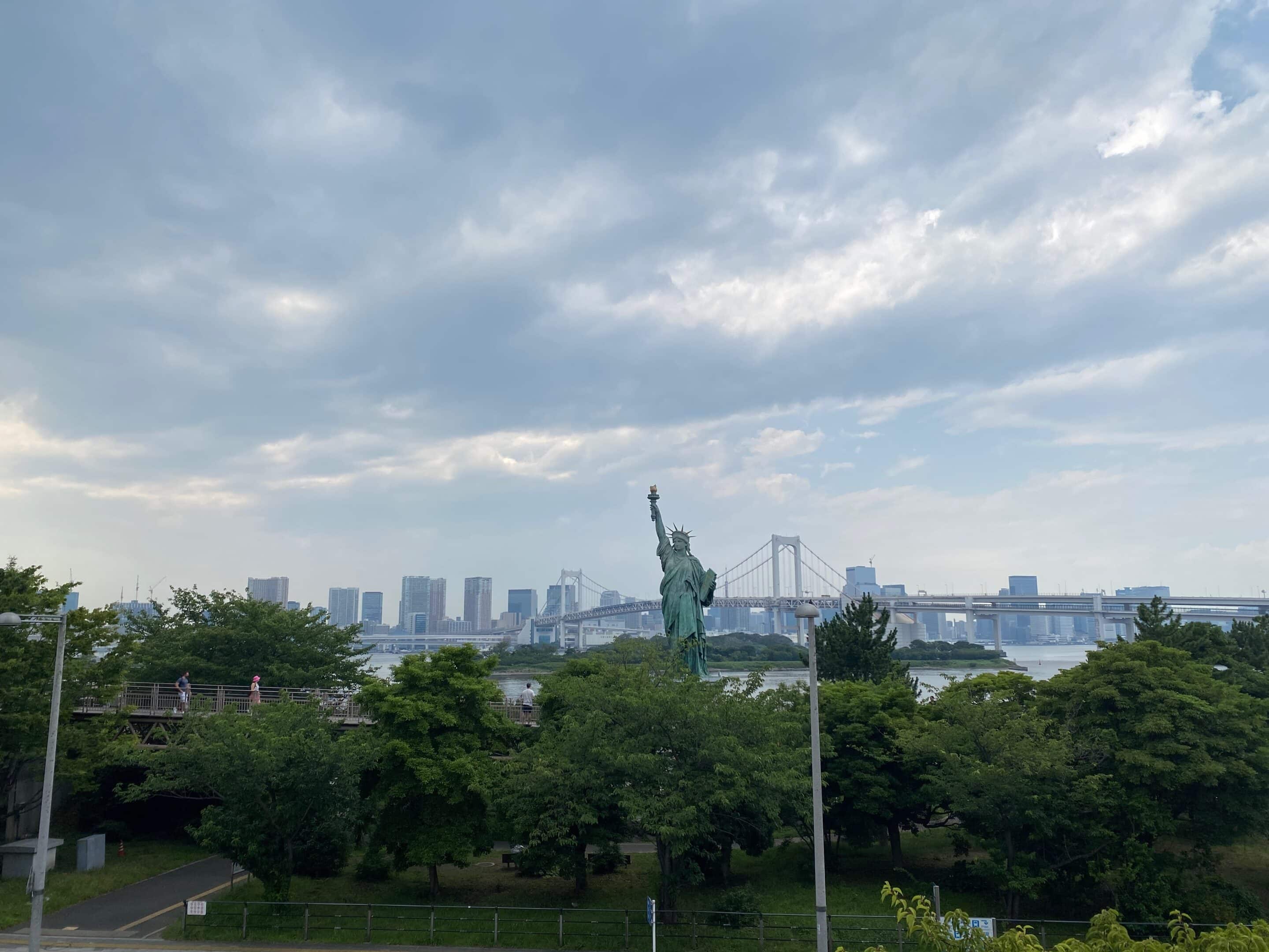 a statue of liberty in the middle of trees and a bridge