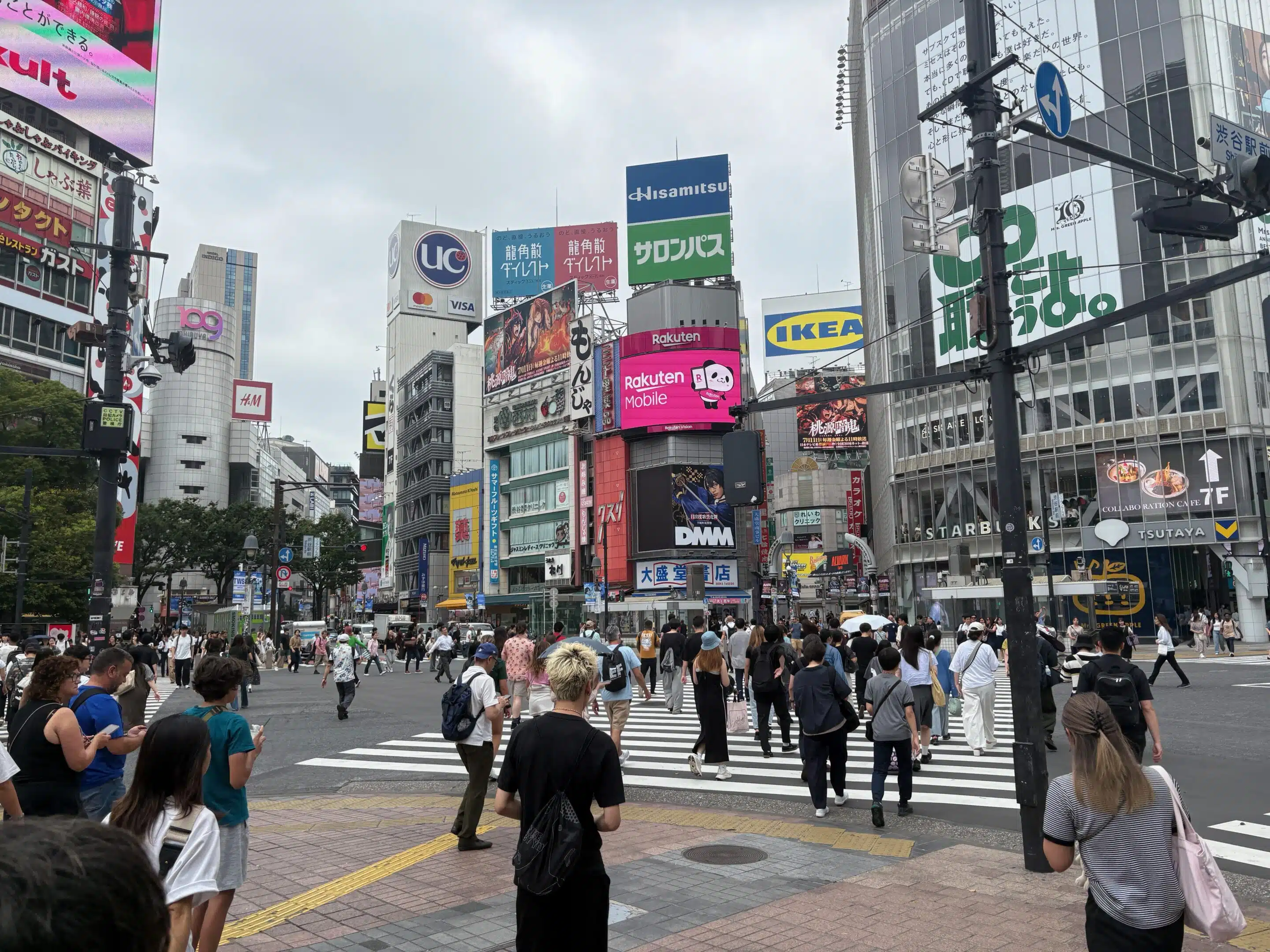 a group of people walking on a street with buildings in the background