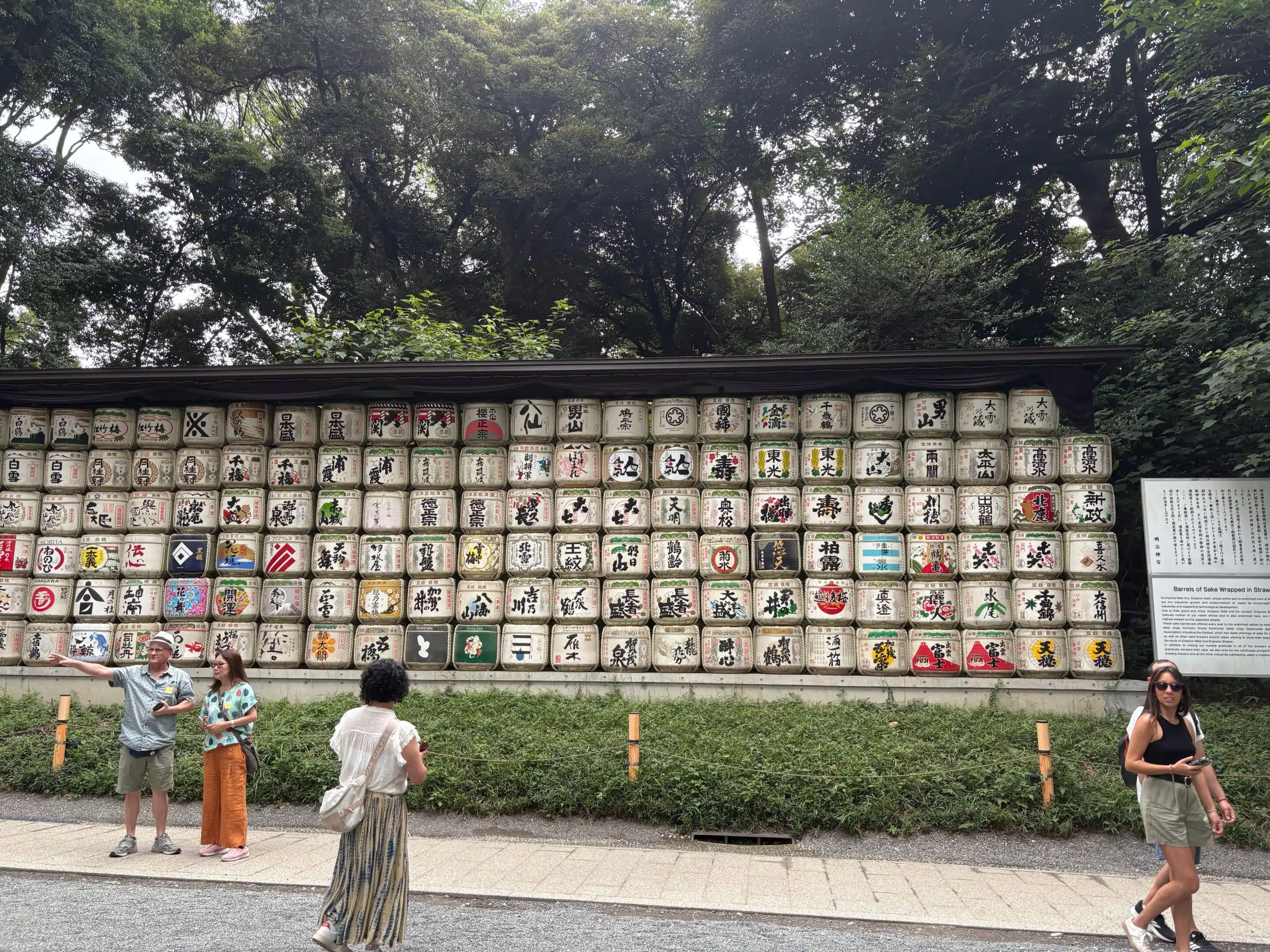 a group of people standing next to a wall with barrels