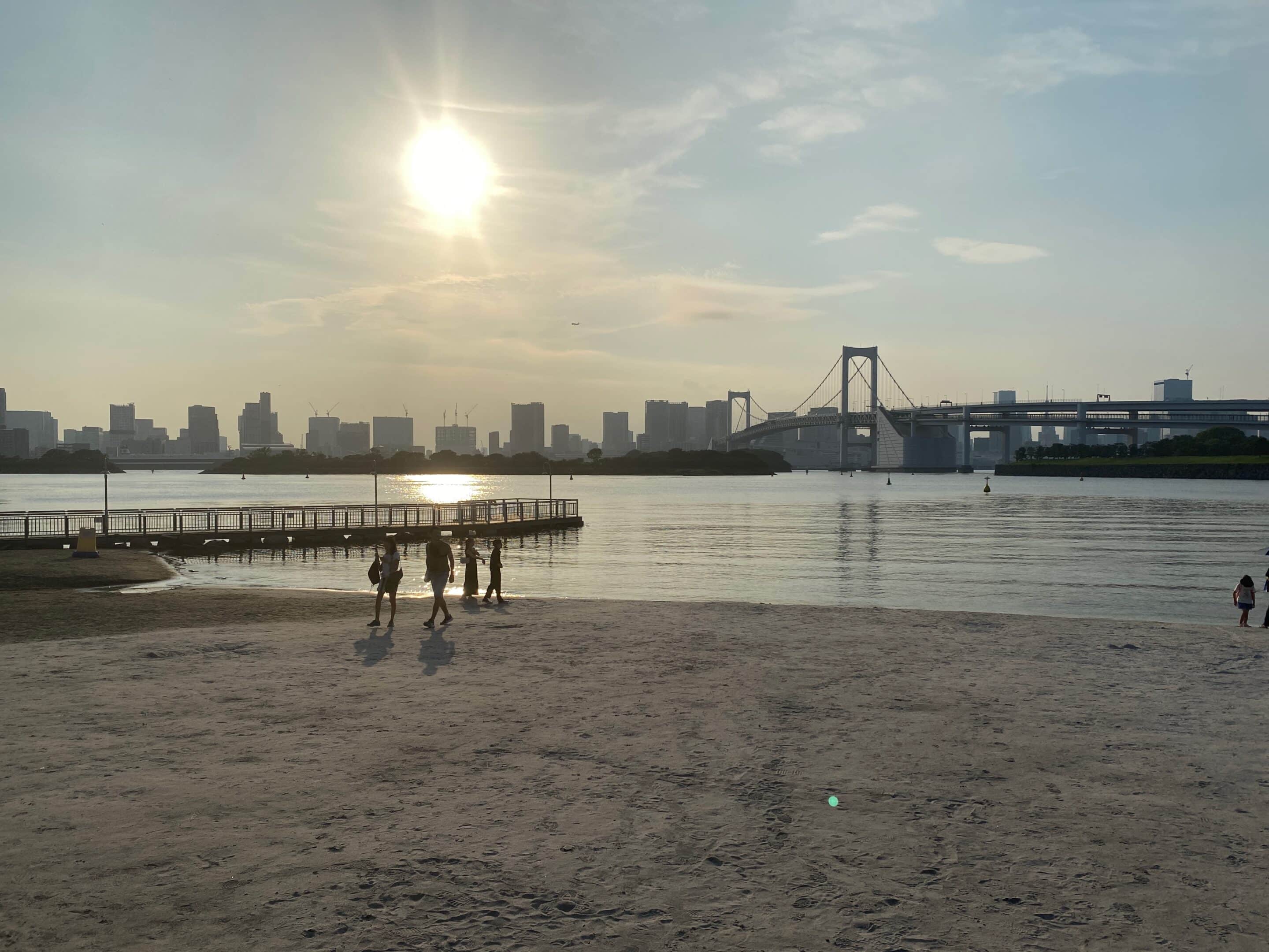 a group of people on a beach with a bridge in the background